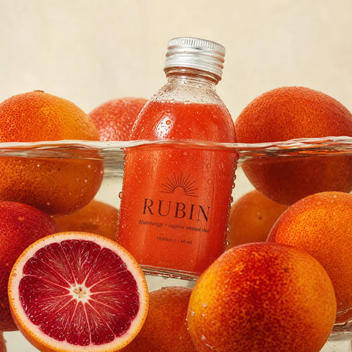 RUBIN Immun-Shot — Flasche zwischen Blutorangen im Wasser